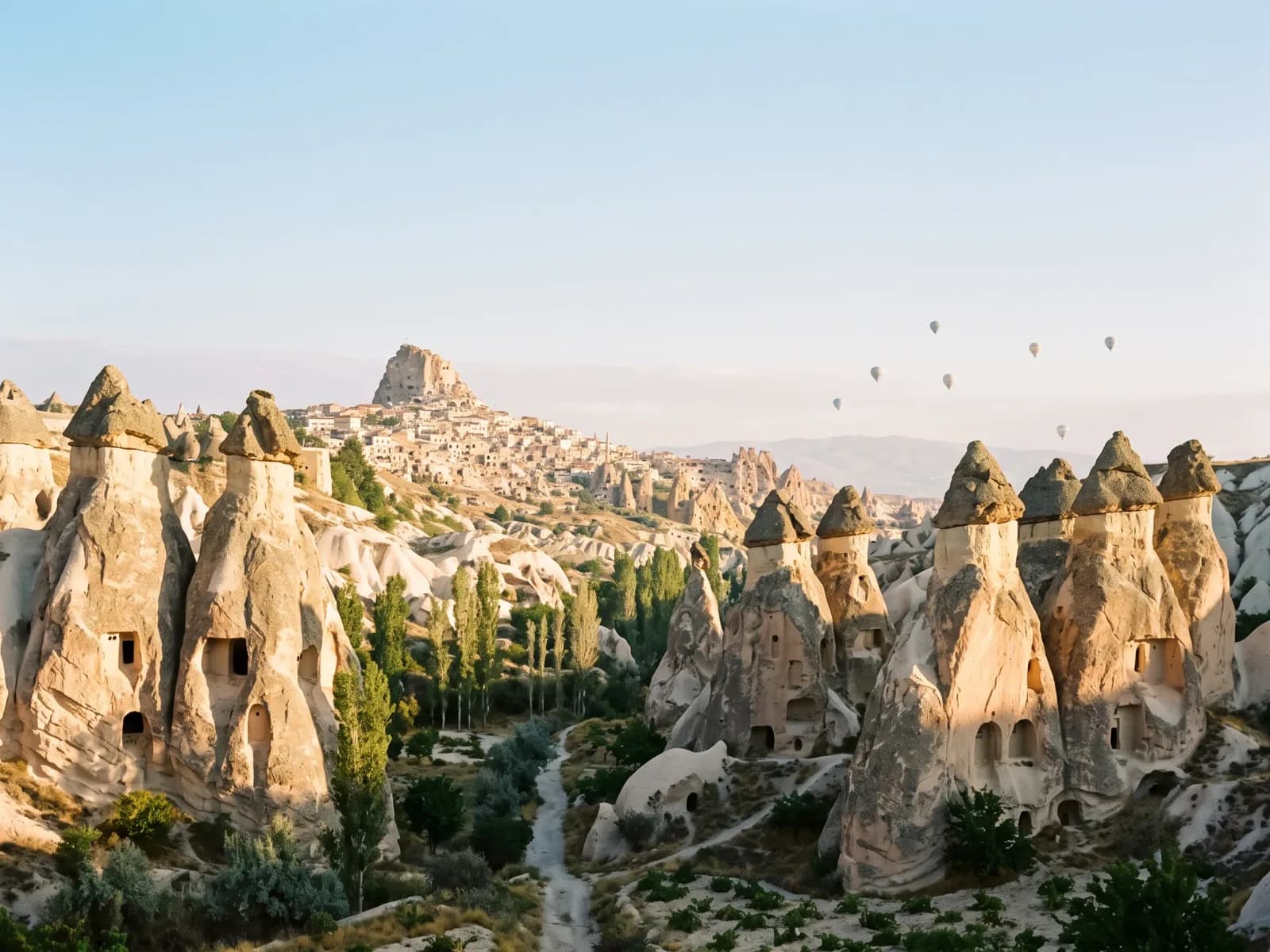Fairy chimneys in the Göreme valley, Cappadocia, at sunrise with balloons in the distance
