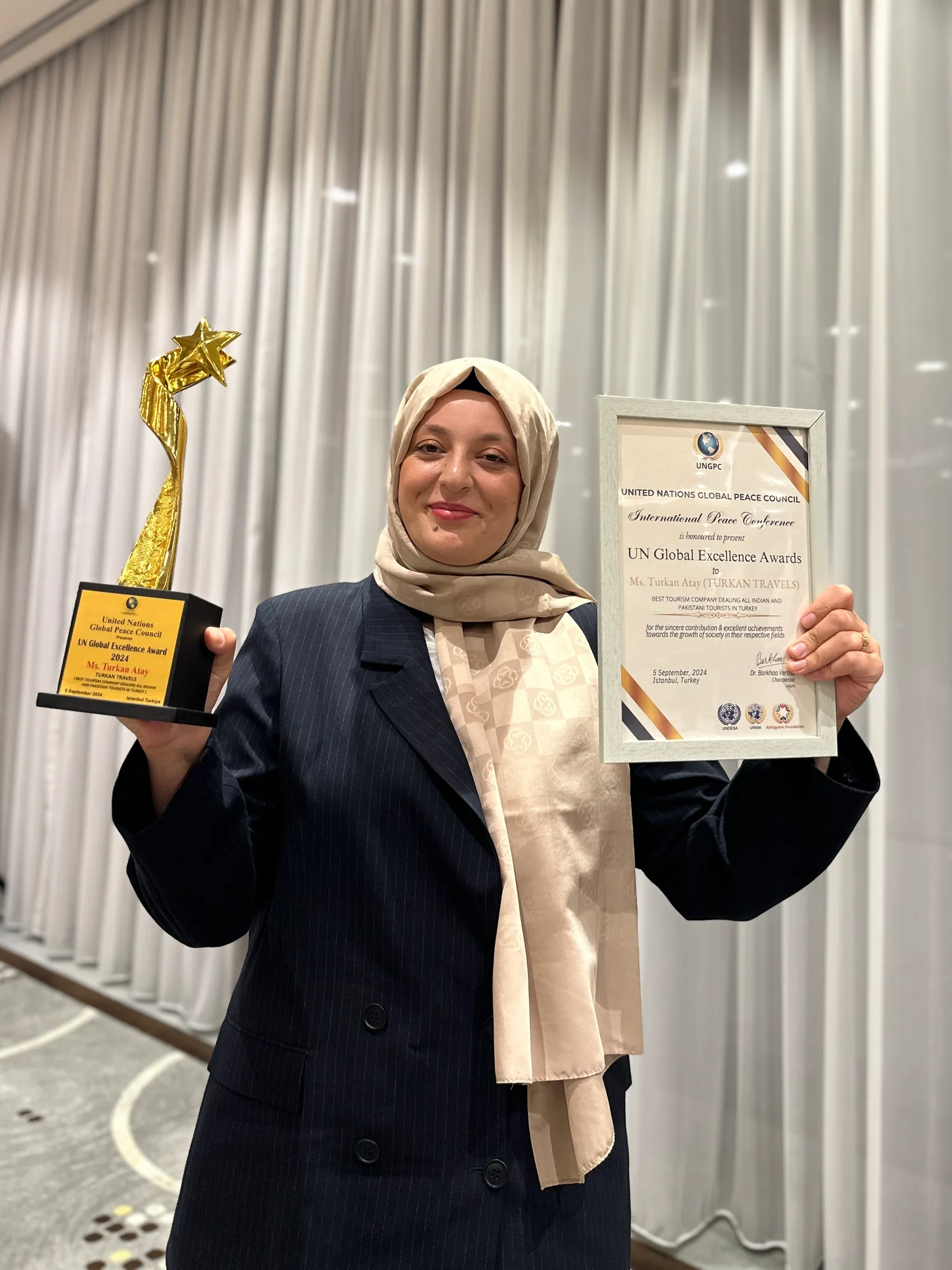 Türkan Atay holding the UN Global Excellence Award trophy and certificate