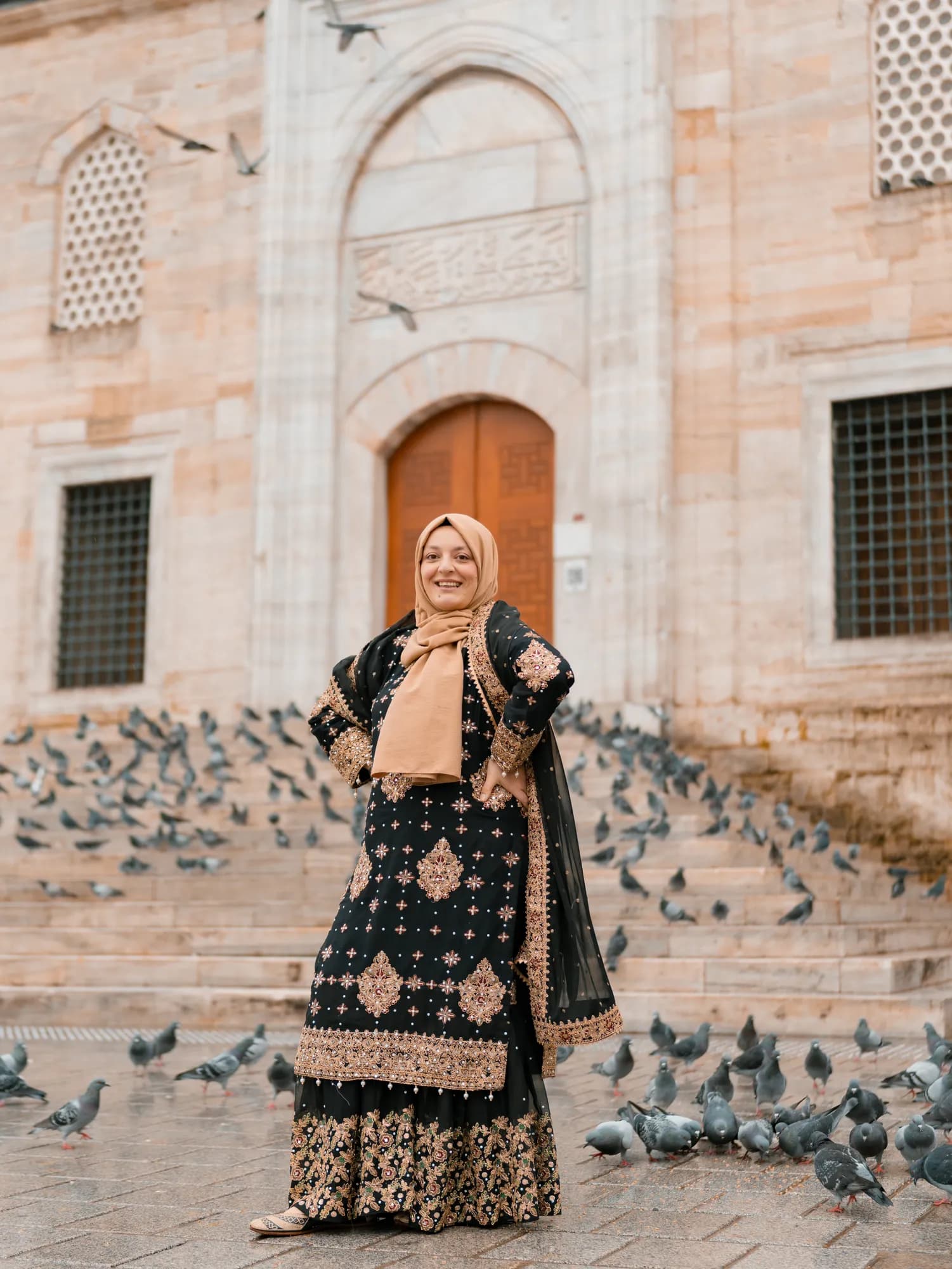 Türkan Atay, founder of Turkan Travels, in the courtyard of an Istanbul mosque, pigeons scattered across the steps behind her