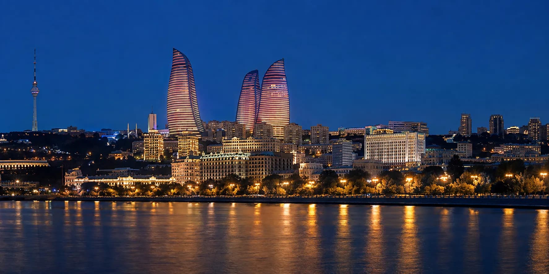 Baku's skyline at blue hour seen across the Caspian, the three Flame Towers lit above the city and the boulevard reflected in the water