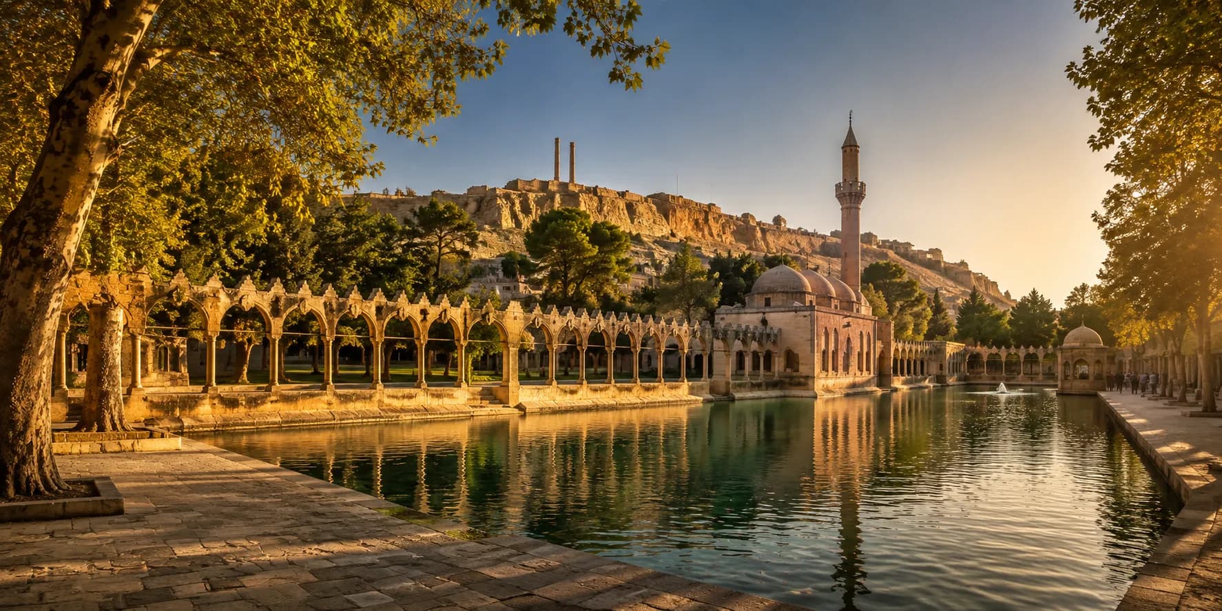 The Balıklıgöl sacred pools in Şanlıurfa, with the Rızvaniye Mosque and its stone arcades reflected in still water