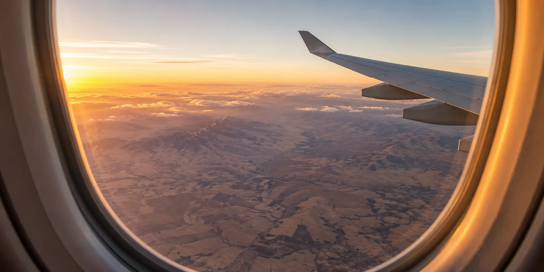 The view from an aircraft window over the Anatolian plateau at sunrise, wing catching the light