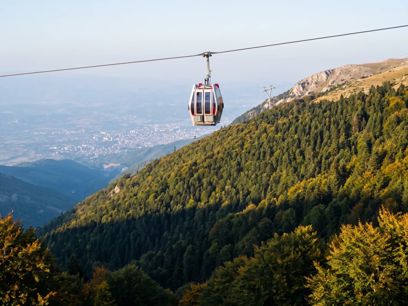 A cable car gondola climbing above the forested slopes of Mount Uludağ near Bursa